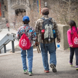A parent with two young children wearing Cornell backpacks
