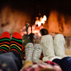 Two adults and one child's socked feet in front of a fire