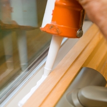 caulking a window frame to prevent air leakage