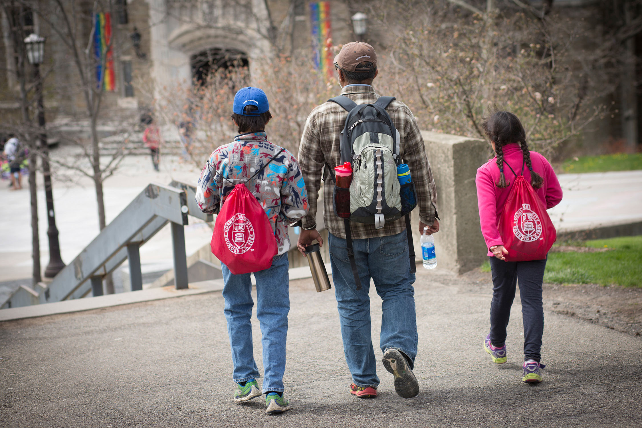 Parent with two young children wearing Cornell backpacks
