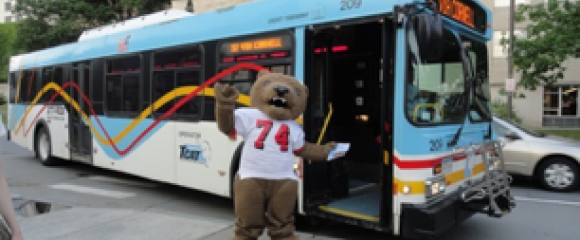 Big Red Bear stands in front of a TCAT bus
