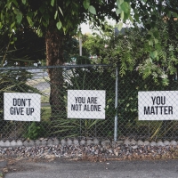 Signs in a front yard read "don't give up," "you are not alone"