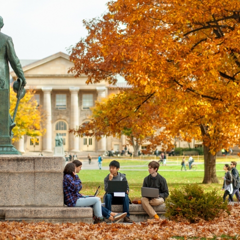 Students study next to Ezra cornell statue