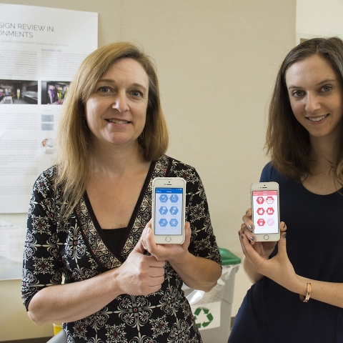 Two students hold up cellphones showing the HumbleBee app interface
