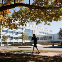 A woman walking down the sidewalk on Tower Road passing Weill Hall
