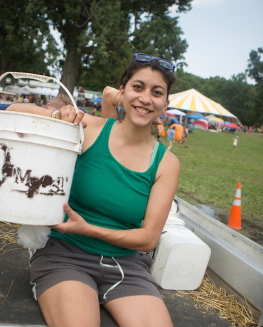 Student sitting on truck holding a compost bucket